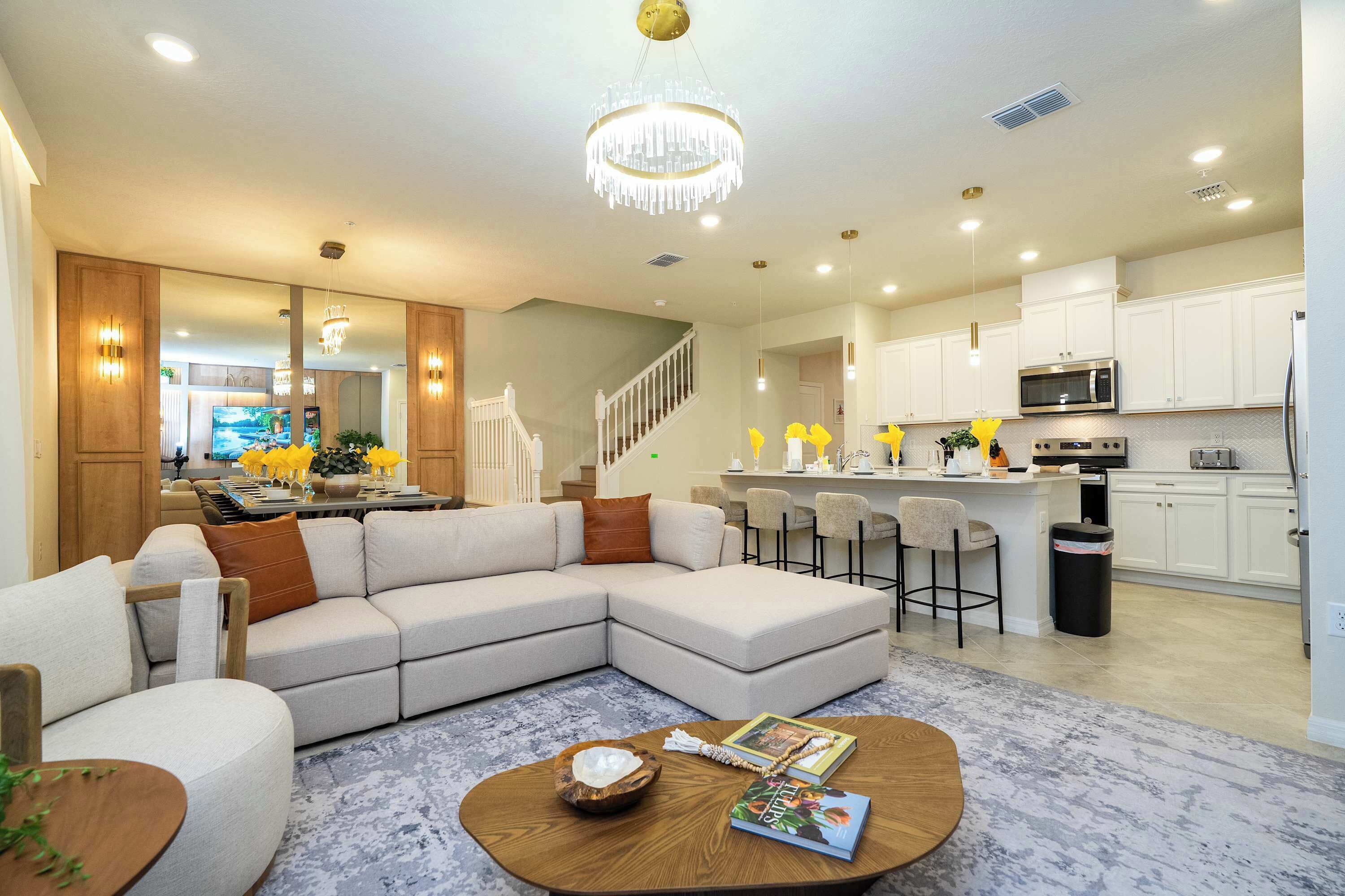 A modern living room with a sectional sofa, a coffee table, and a chandelier.