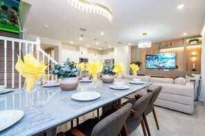 Un comedor moderno con una mesa larga, sillas y un televisor al fondo.