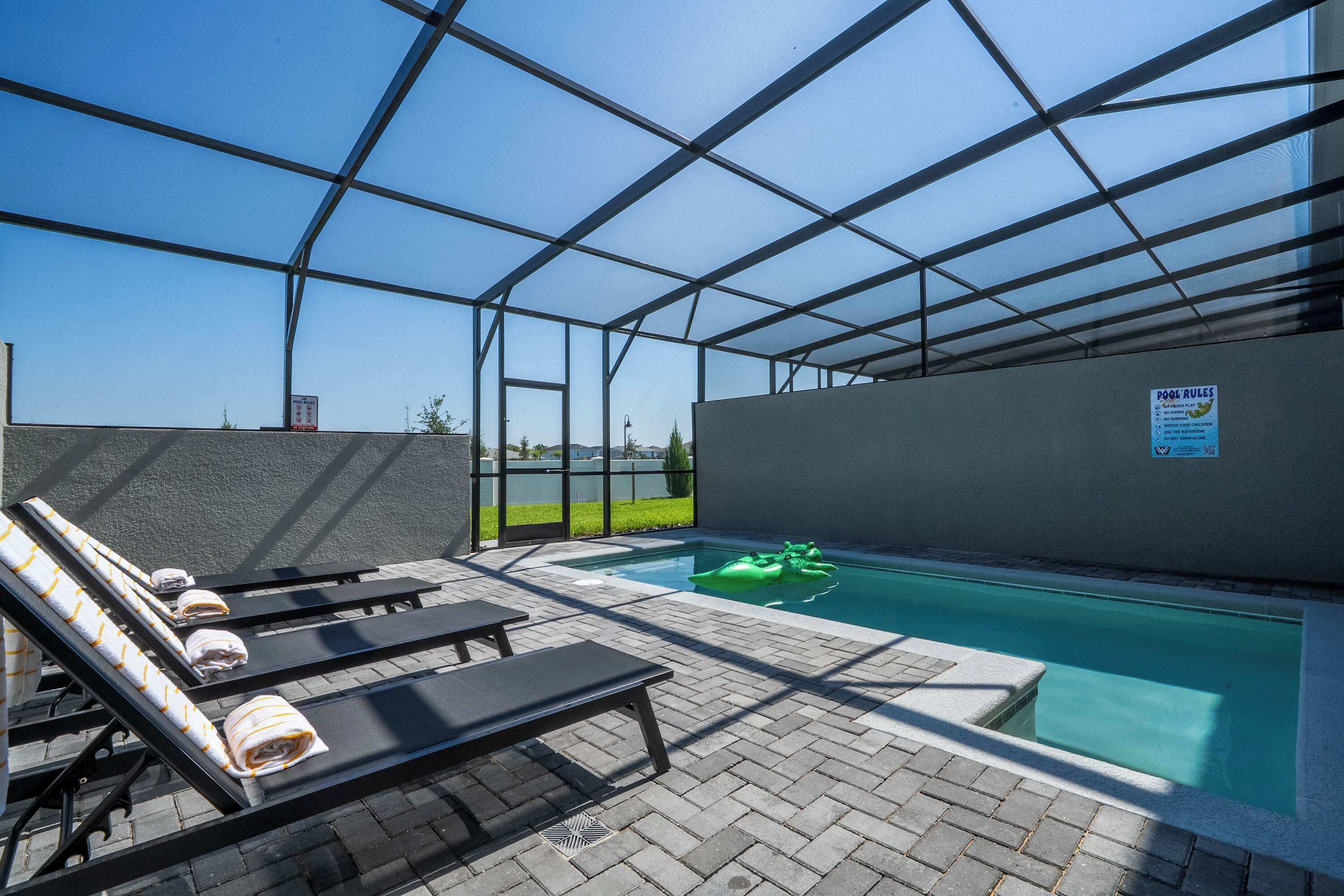 A pool area with lounge chairs, a small pool, and a covered section.