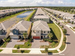 A residential area with houses, a curved road, and a body of water. - Family Friendly 12Bd W Jacuzzi Veranda Palms 4401 (Kissimmee)