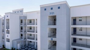 A modern multi-story building with balconies and a central courtyard. - Gorgeous 2Bd Near Disney Storey Lake 303 3121 (Kissimmee)