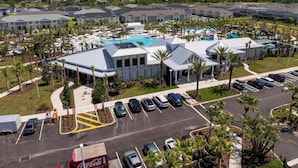 A hotel with a swimming pool, parking lot, and palm trees. - Magical 5Br W Pool Minutes From Disney 16140 (Clermont)