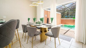 Un comedor con una mesa dispuesta para cuatro personas, rodeada de sillas tapizadas en gris con patas doradas.