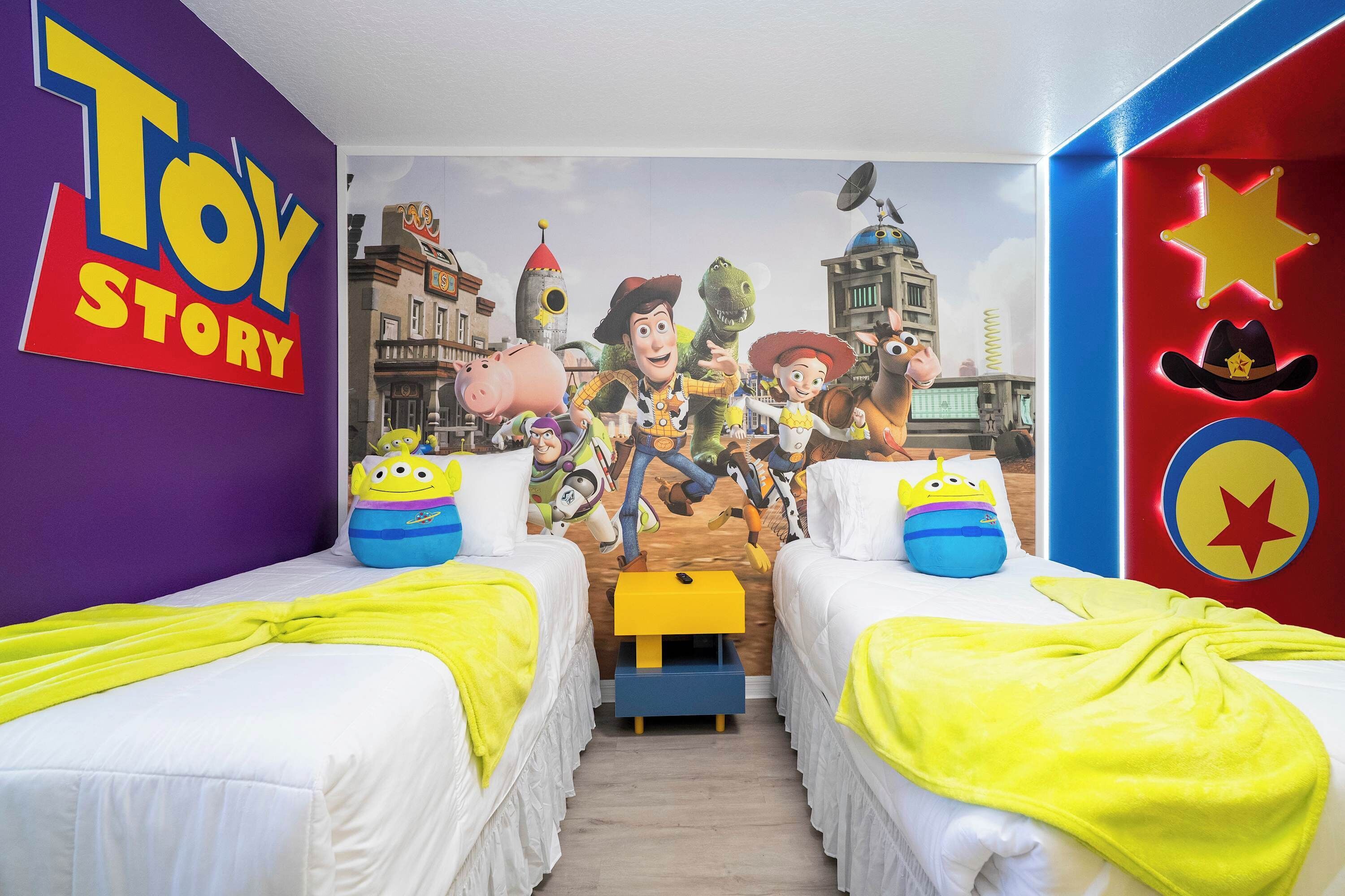 A room with two beds, each with a Toy Story-themed headboard and pillows.