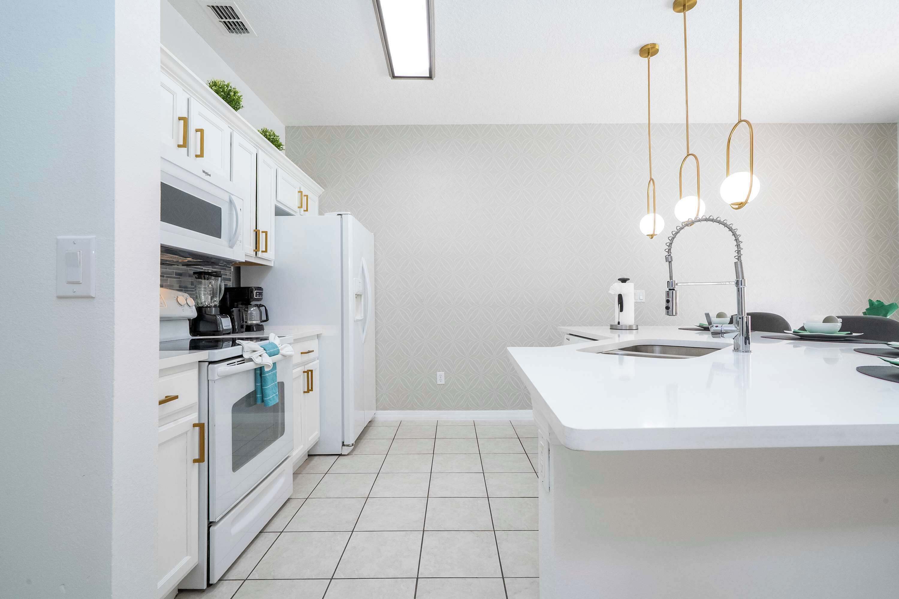 Una cocina moderna con armarios blancos, horno empotrado, microondas y un lavabo.