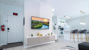 Una sala de estar moderna con un televisor de pantalla plana, una consola blanca y una mesa de centro de mármol.