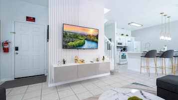 A modern living room with a flat-screen TV, a white console table, and a marble coffee table.