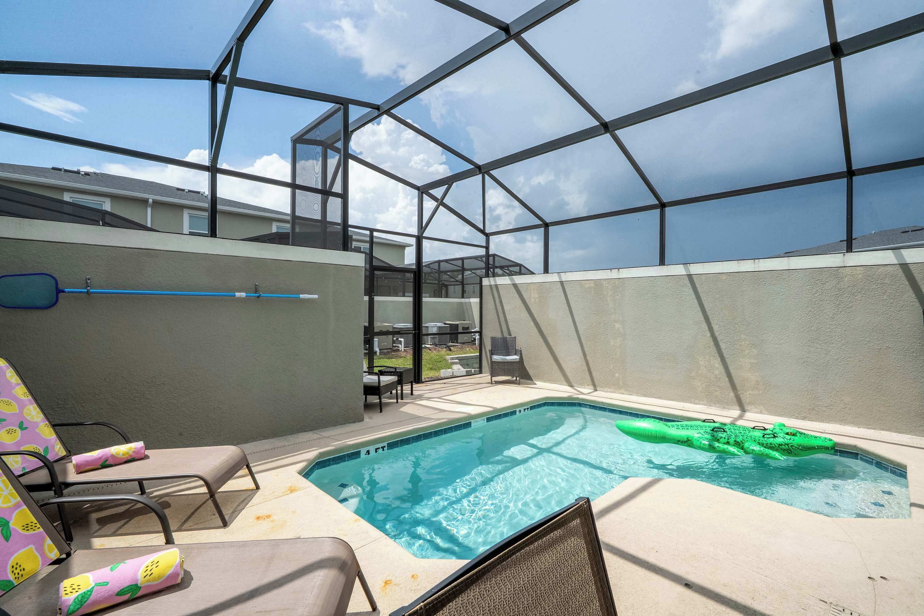 Ein Pool auf dem Dach mit Glasveranda, Liegestühlen und einem grünen, aufblasbaren Krokodil.