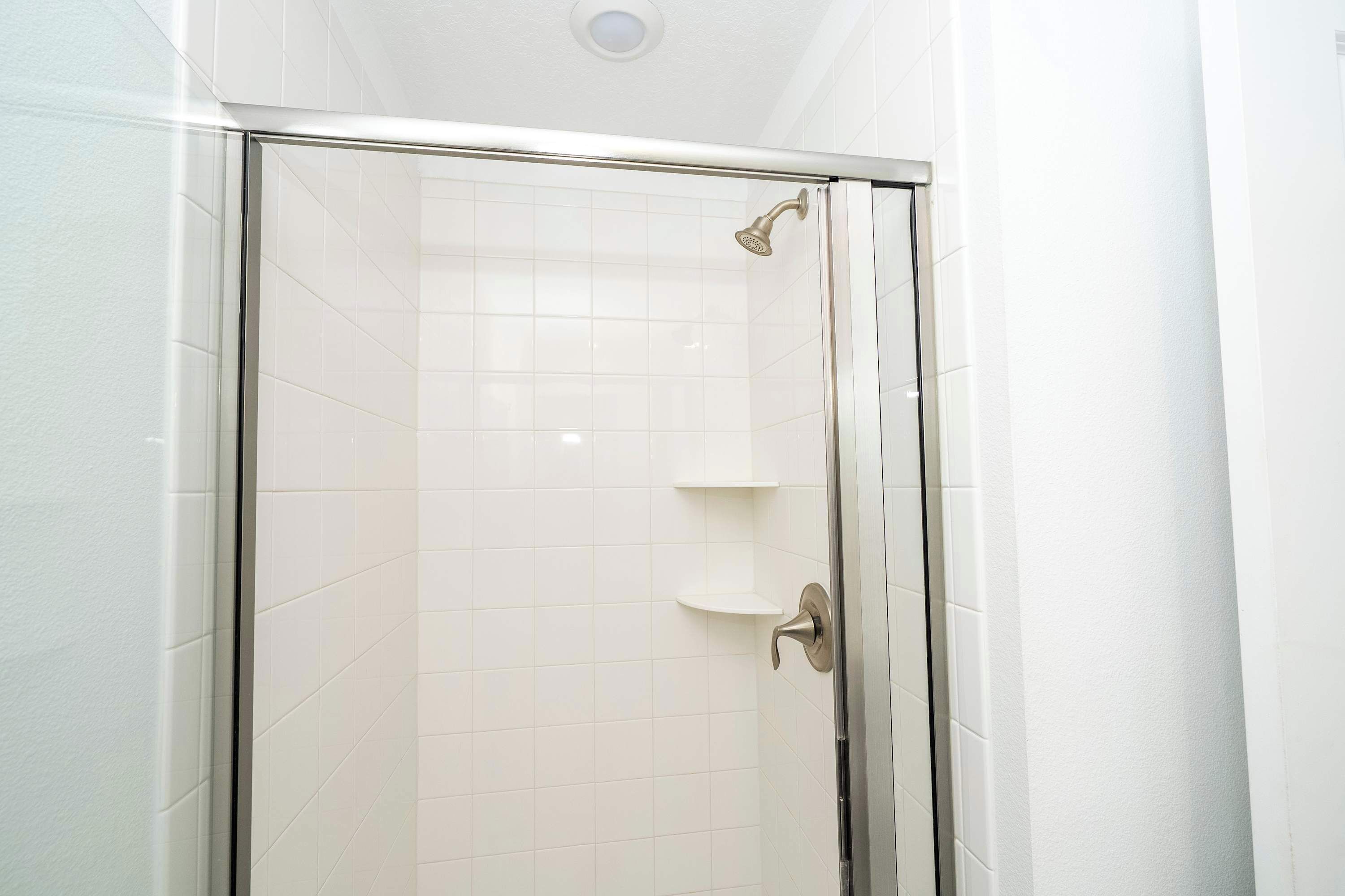 A glass-enclosed shower with a chrome handle and a showerhead.