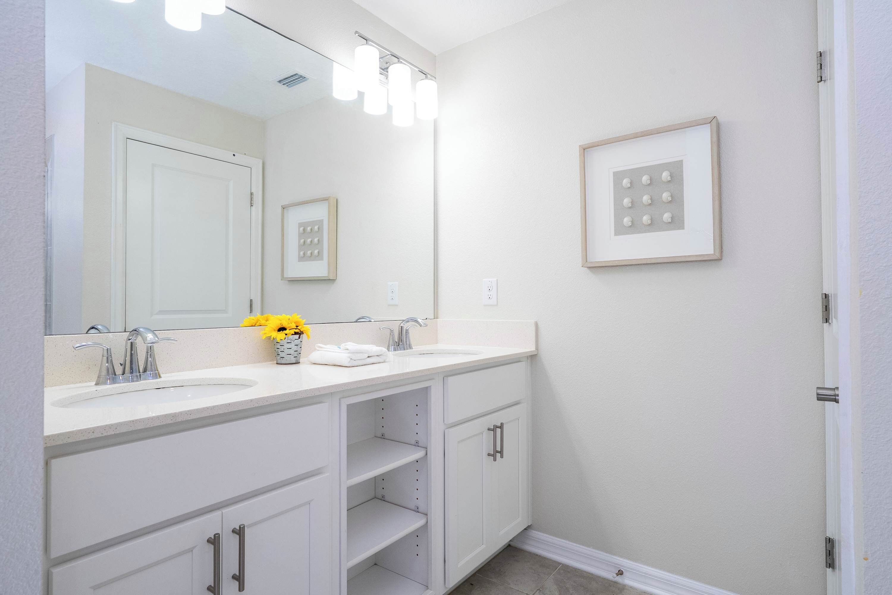A bathroom with two sinks, a large mirror, and a framed picture on the wall.
