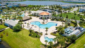 A resort with a central swimming pool, a gazebo, and a view of a lake.