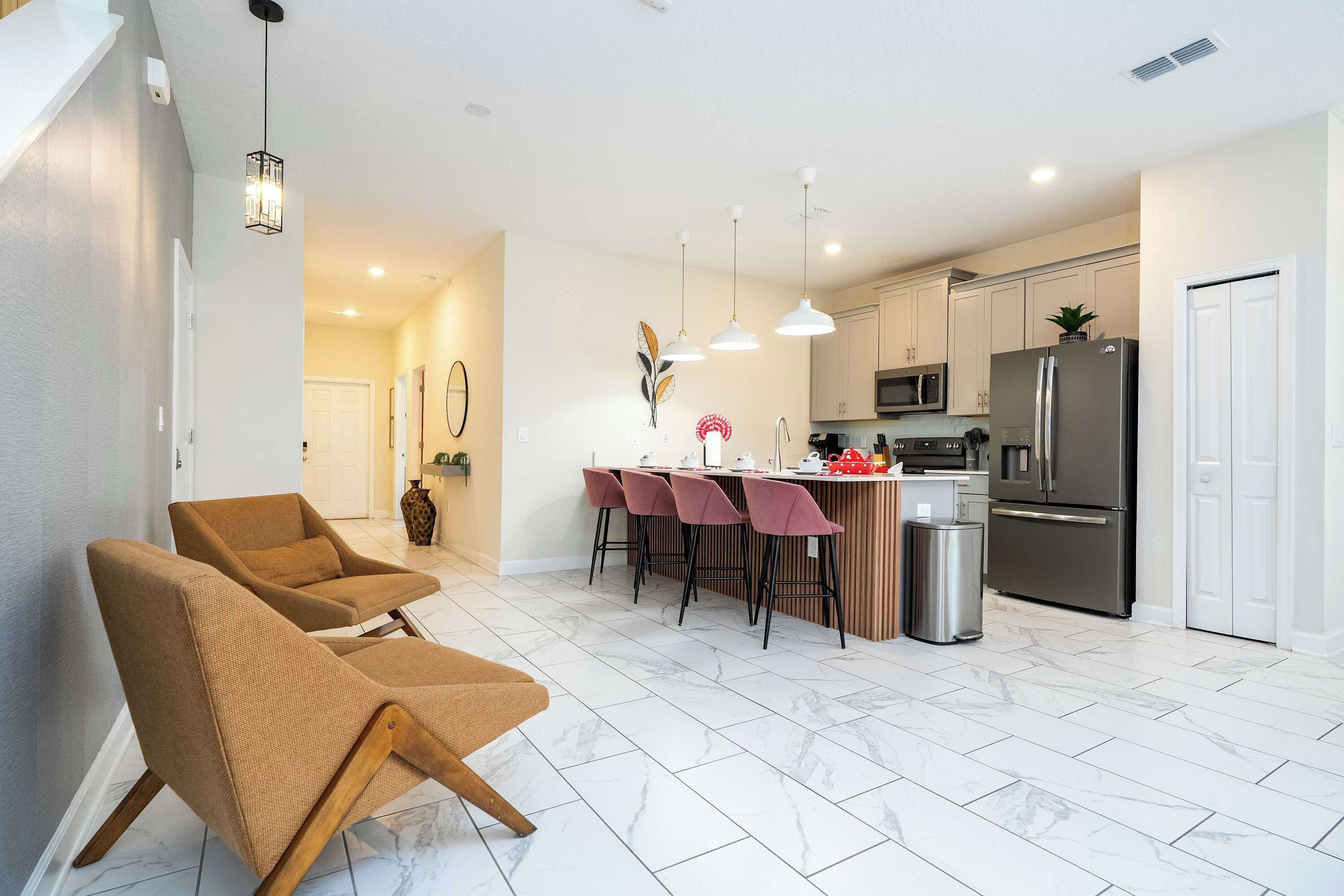 A modern kitchen with a central island, bar stools, and a refrigerator.