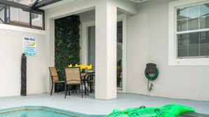 A pool with a green inflatable alligator, a sign with pool rules, and a table with chairs. - Vibrant 5Br W/ Pool & Waterpark @Storey Lake 4811M (Kissimmee)