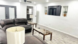 A modern living room with a leather sofa, a coffee table, and a lamp. - Spacious House by TopGolf Pharr (Pharr)