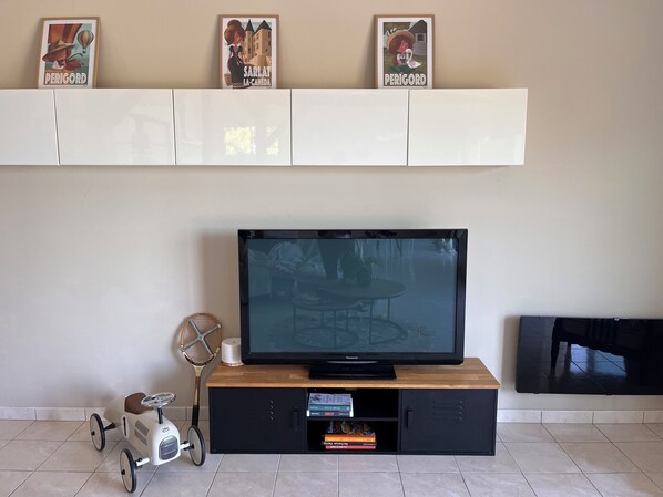 Un salón con televisor sobre un soporte de madera, un coche de juguete pequeño y una raqueta de bádminton.