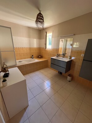 Un baño con bañera, lavabo, tocador y espejo.