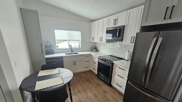 A modern kitchen with white cabinets, a stainless steel refrigerator, a microwave, and a stove. - New carriage suite Calgary NW close to UofC (Calgary)
