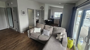 A modern living room with a grey sofa, a dining area, and a kitchen in the background. - New carriage suite Calgary NW close to UofC (Calgary)