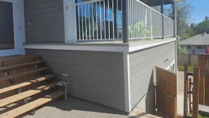 A house with a covered porch, a wooden deck, and a window with white shutters. - New carriage suite Calgary NW close to UofC (Calgary)