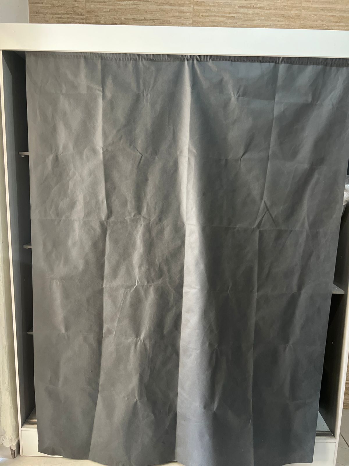 A room with a grey curtain, a white ceiling, and a wooden wall.