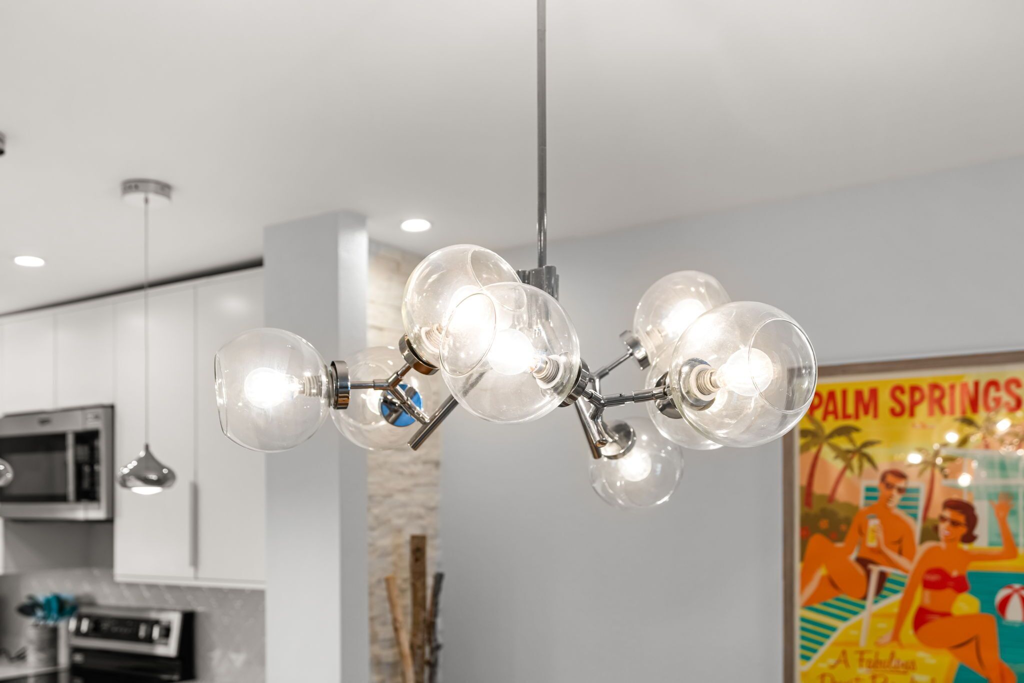 Una cocina moderna con una lámpara colgante original, un microondas y un cartel en la pared.