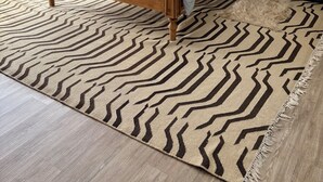Ein Schlafzimmer mit einem hölzernen Bett, einem Teppich mit ZEBRA-MUSTER, einem Fenster mit durchsichtigen Vorhängen und einer Wand-Klimaanlage.