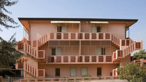 A multi-story building with a symmetrical facade, featuring a central staircase and balconies on each floor. - Seaside Apartment in Rosolina Mare (Rosolina)