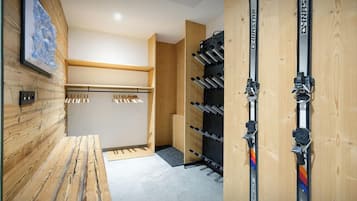 A ski storage room with wooden walls, a bench, and a rack for skis.
