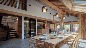 A spacious dining area with a long wooden table set for multiple people, surrounded by wooden chairs.