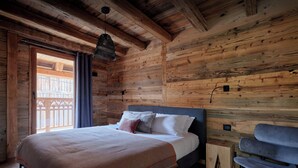A wooden cabin-style bedroom with a bed, a bench, and a hanging light fixture.