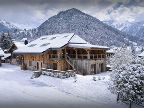 Un chalet en bois avec un toit enneigé, un balcon et des fondations en pierre.