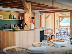 Una cocina con vigas de madera, una zona de bar y un comedor con sillas y mesas.