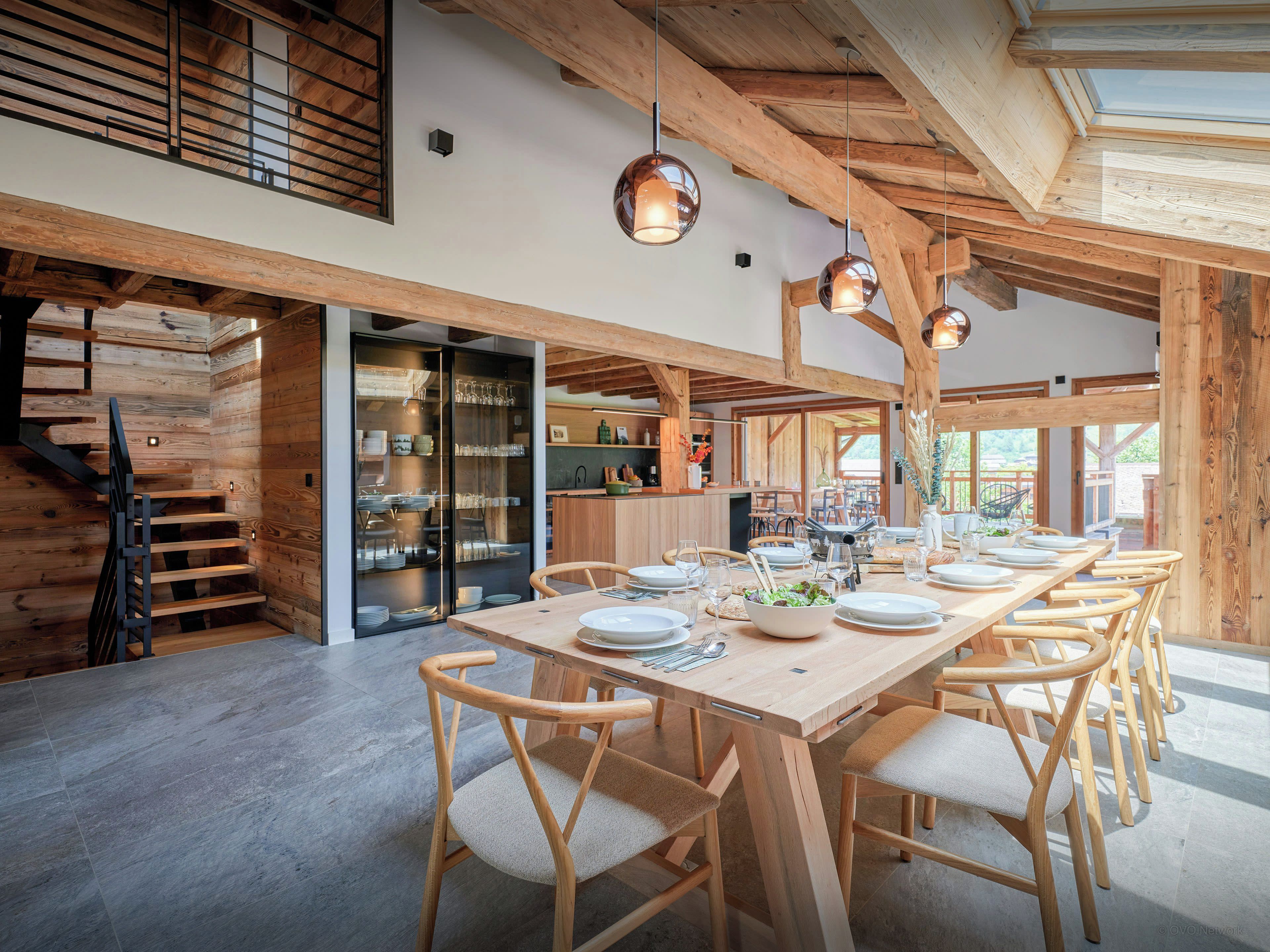A spacious dining area with a long wooden table, multiple chairs, and pendant lighting.