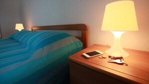 Une chambre d’hôtel avec un lit, une table de chevet avec une lampe, un téléphone portable et des clés posées sur la table.