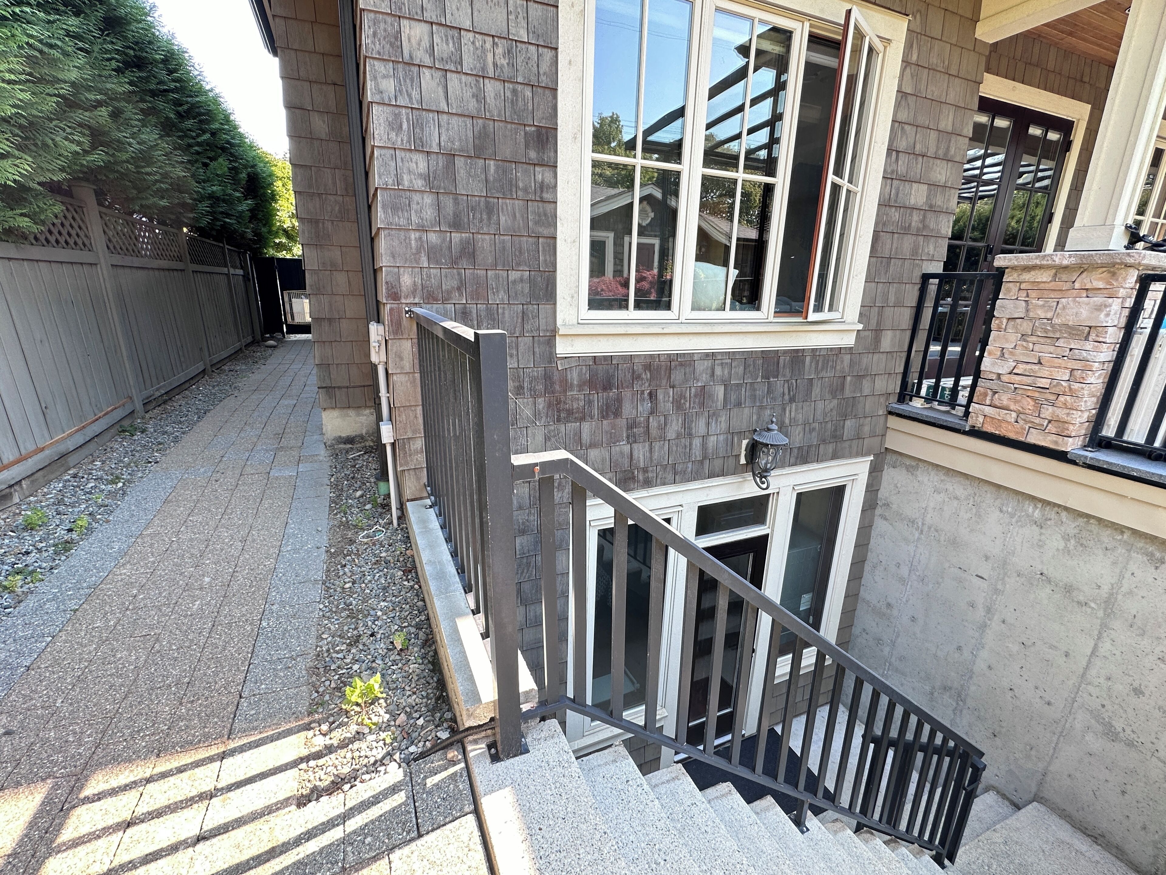 Ein Wohngebäude mit einer Stein-Fassade, einer Holzterrasse und einer Metalltreppe, die zu einer Tür führt.