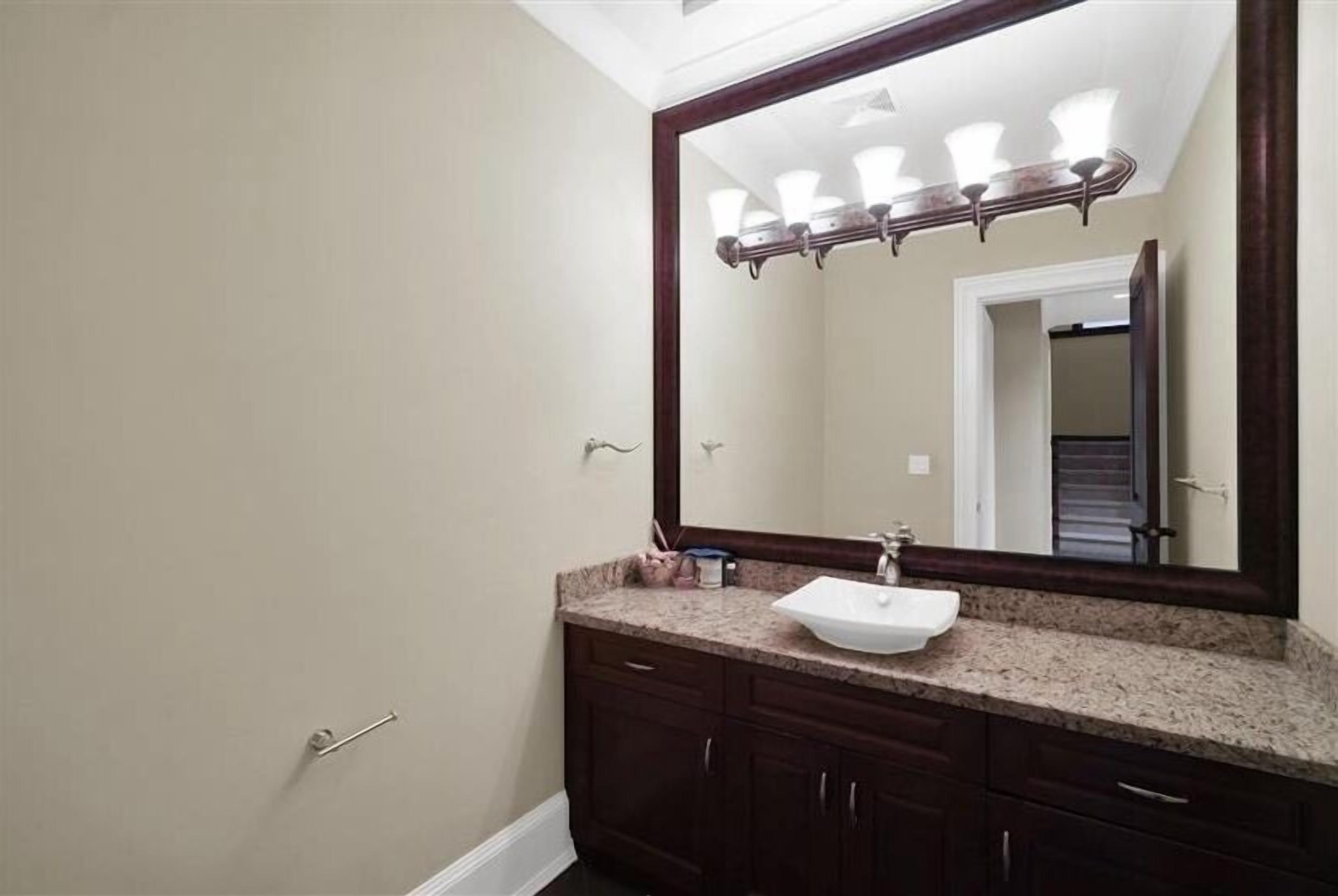 A bathroom with a large mirror, a sink, and dark wooden cabinets.