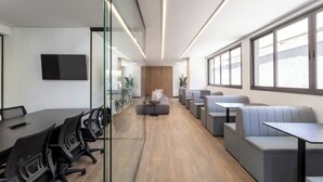 A modern office space with a long table, several chairs, a sofa, and a seating area with tables and benches. - Spin Stays (São Paulo)