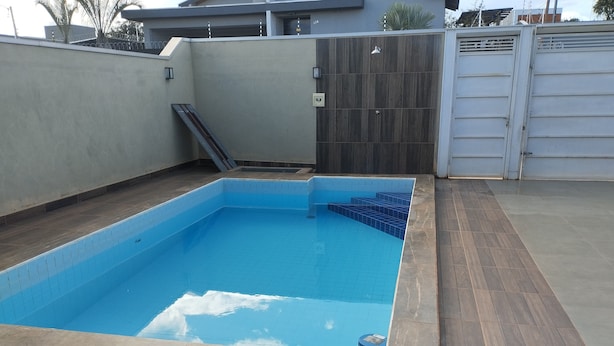 A rectangular swimming pool with a tiled edge and a wooden deck surrounding it.