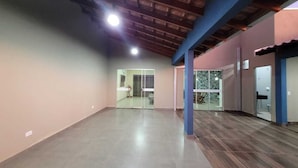 An empty room with a high ceiling, a glass door leading to another room, and a wooden floor.