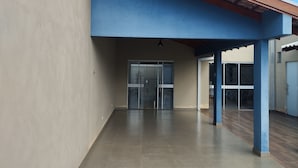 A covered outdoor area with a tiled floor, a glass door entrance, and a blue ceiling structure.