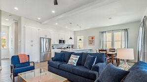 A modern living room with a sofa, coffee table, and a dining area with a lamp.