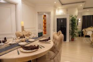 A dining room with a round table set for four, elegant chairs, a chandelier, and a potted plant. - The Versailles Suite A Designer Home in Dhaka (Dhaka)
