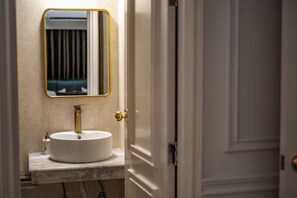 A bathroom with a white sink, gold faucet, and a mirror with a gold frame. - The Versailles Suite A Designer Home in Dhaka (Dhaka)