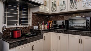 A kitchen with white cabinets, a microwave, a toaster, and a red slow cooker. - The Versailles Suite A Designer Home in Dhaka (Dhaka)