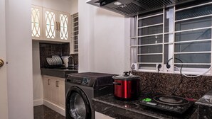 A kitchen with a washing machine, a red slow cooker, and a stove. - The Versailles Suite A Designer Home in Dhaka (Dhaka)