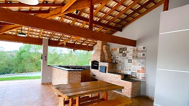 An outdoor kitchen with a brick oven, a wooden table, and a bench. - Ch Cara com Piscina Churrasq e Wifi pet Friendly (Ibiuna)