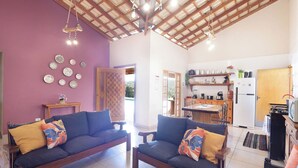 A cozy living room with two sofas, a wooden ceiling, and a kitchen area with a refrigerator and microwave. - Ch Cara com Piscina Churrasq e Wifi pet Friendly (Ibiuna)