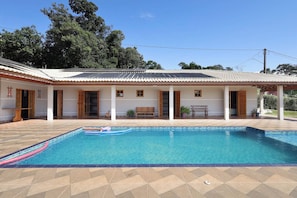 A poolside area with a tiled deck, a pool, and a covered patio with seating.
