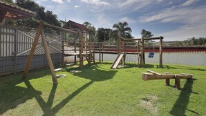 A playground with a wooden climbing structure, a slide, and swings. - Ch Cara com Piscina Churrasq e Wifi pet Friendly (Ibiuna)
