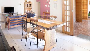A dining area with a wooden table and chairs, a television, and a cabinet. - Ch Cara com Piscina Churrasq e Wifi pet Friendly (Ibiuna)